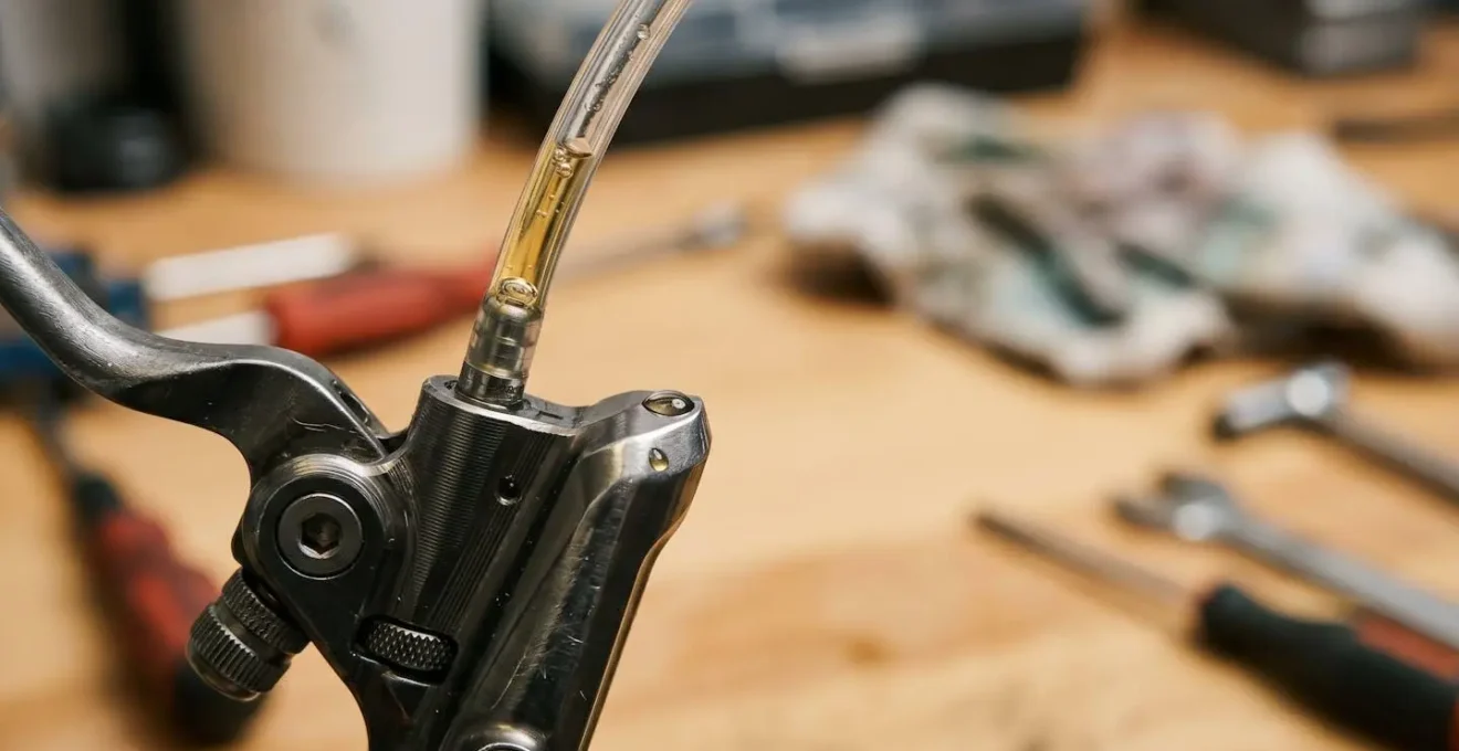 Close-up of a mountain bike hydraulic brake lever being bled with clean fluid visible in transparent tubing