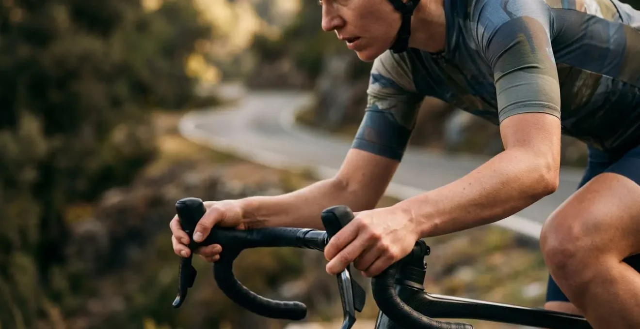 Professional cyclist gripping flared drop bars during technical descent with focused posture and confident body position