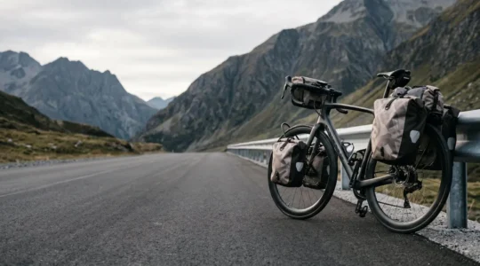 Professional cyclist on aggressive race geometry bicycle struggling with balance under heavy touring panniers load