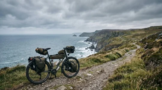Touring bicycle with loaded panniers on dramatic UK coastal path with rugged cliffs and stormy sea
